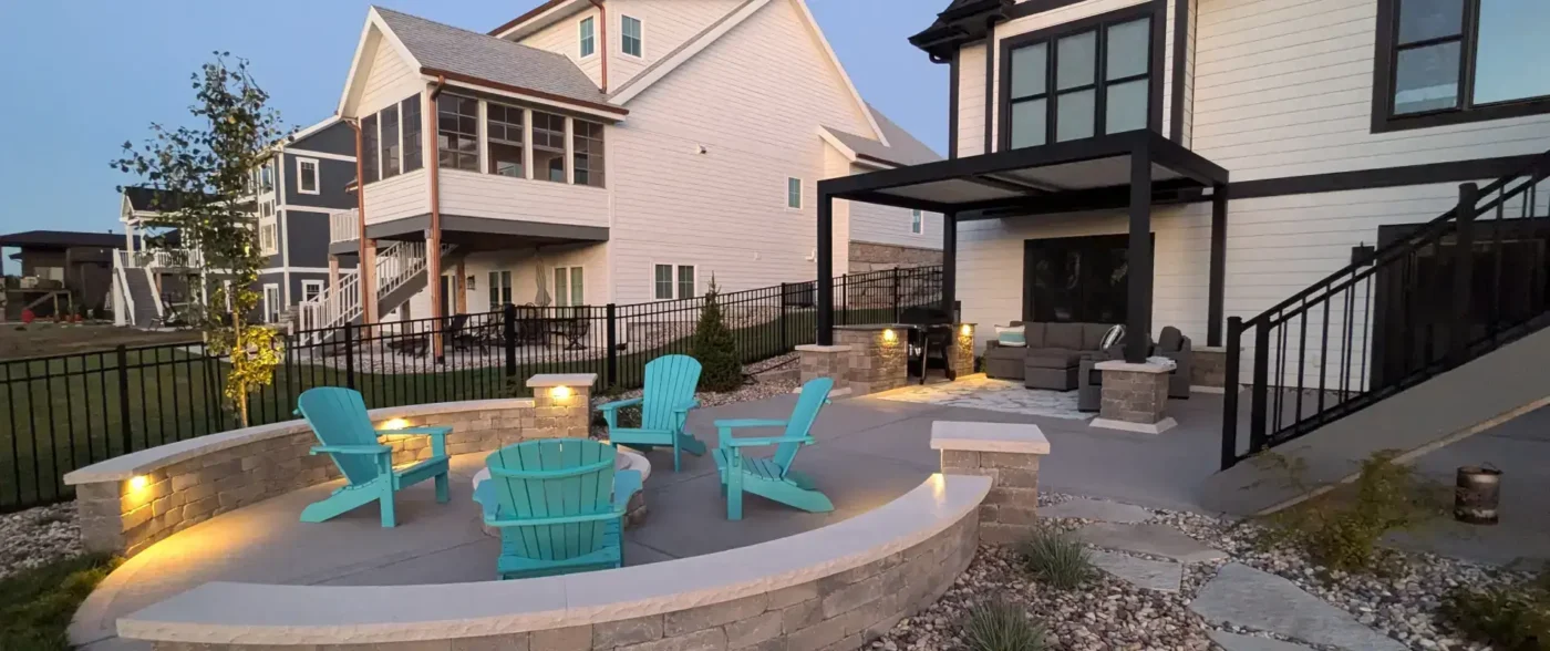 Beautifully designed outdoor living space with stone patio, fire pit seating area, and landscape lighting by Carrington Lawn & Landscape in Middleton, WI
