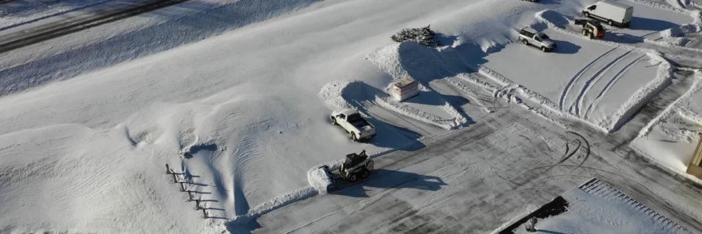 Overhead view of crews cutting through deep drifts and widening lanes across a commercial property during a commercial snow removal service by Carrington Lawn & Landscape in Middleton, Madison, and the greater Dane County area