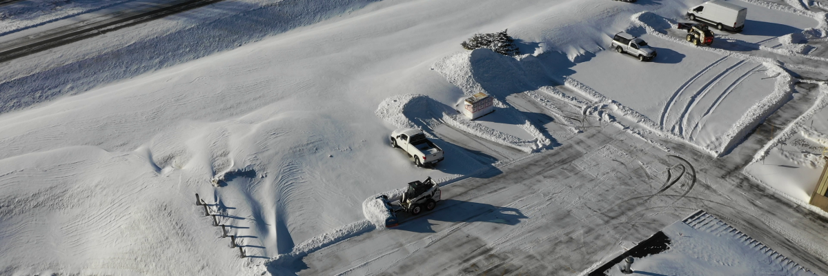 Overhead view of crews cutting through deep drifts and widening lanes across a commercial property during a commercial snow removal service by Carrington Lawn & Landscape in Middleton, Madison, and the greater Dane County area