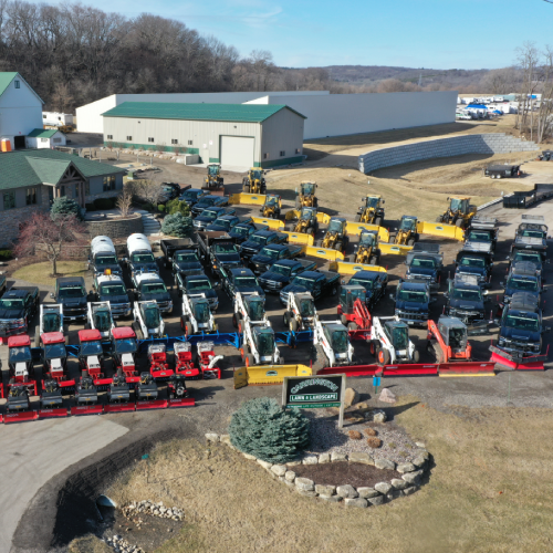 Aerial view of organized rows of plow trucks, loaders, and skid steers prepared for a commercial snow removal service by Carrington Lawn & Landscape in Middleton, Madison, and the greater Dane County area