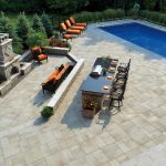 An elegant hardscape design with a stone firepit, outdoor kitchen and swimming pool in Middleton, WI