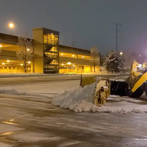 Carrington Lawn & Landscape loader plowing snow at night demonstrating Salt Wise Certification commitment in Middleton, WI