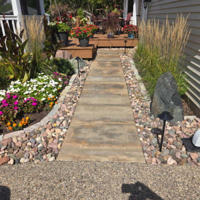 Close-up of a stone pathway through a garden, with colorful flowers, decorative rocks, and tall grasses by hardscape design contractors in Middleton, WI