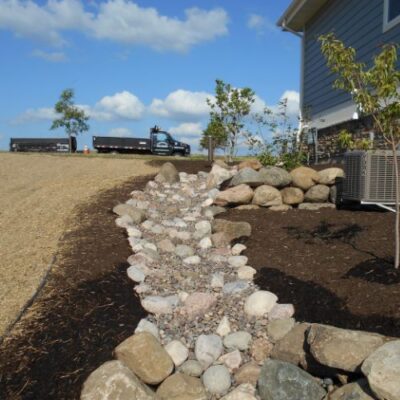 Newly landscaped area with a decorative rock feature resembling a dry creek by Carrington Lawn & Landscape hardscape design in Middleton, WI