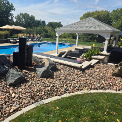 Modern backyard pool with a dark rectangular water feature, surrounded by a patio with lounge chairs by Carrington Lawn & Landscape