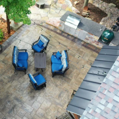 High-angle view of outdoor kitchen, patio, and blue cushioned chairs for outdoor kitchen planning by Carrington Lawn & Landscape in Madison