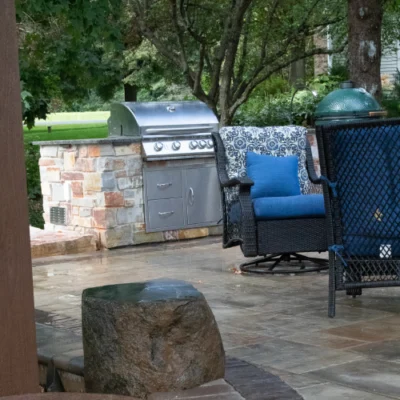 Outdoor kitchen featuring built-in grill and comfortable blue cushioned patio chairs for outdoor kitchen planning by Carrington Lawn & Landscape in Madison