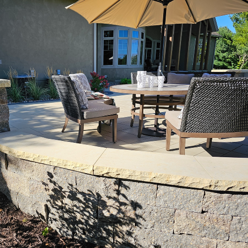 Outdoor table and chairs with umbrella on a multi level paver patio near a house in Wisconsin