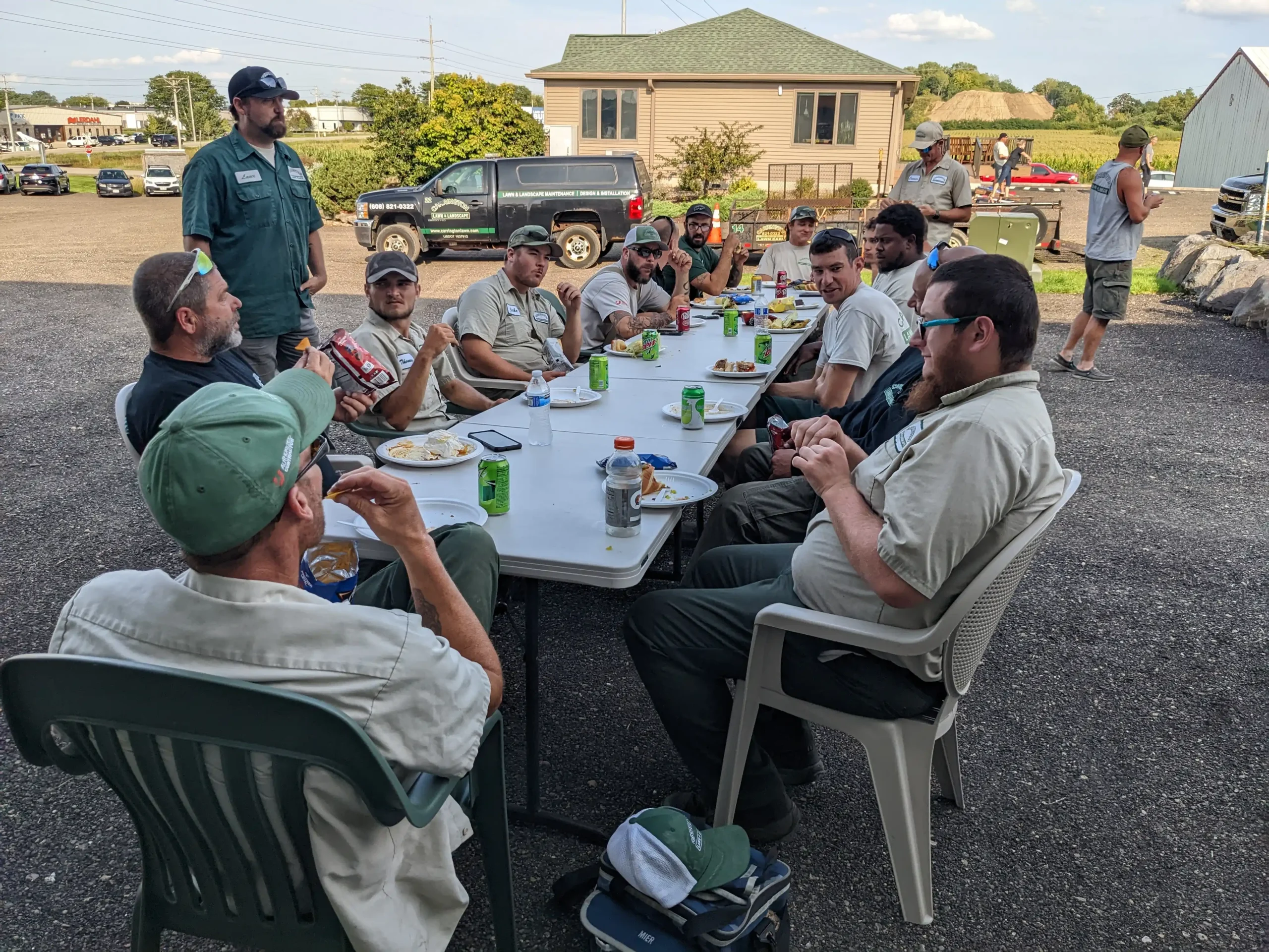 Carrington Lawn & Landscape team members gathered outside in Madison, sharing a meal together at long tables during a company lunch break