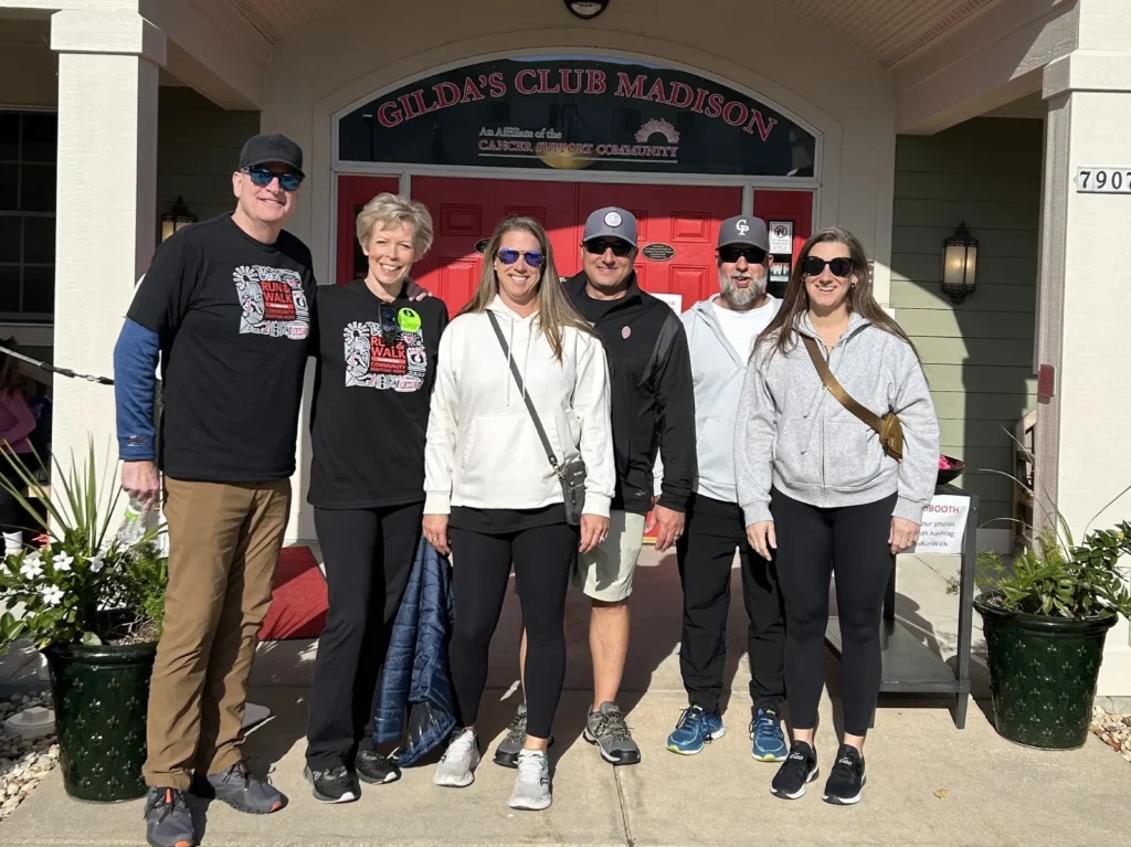 Six Carrington Lawn & Landscape team members smiling outside a community building at a local event in Madison
