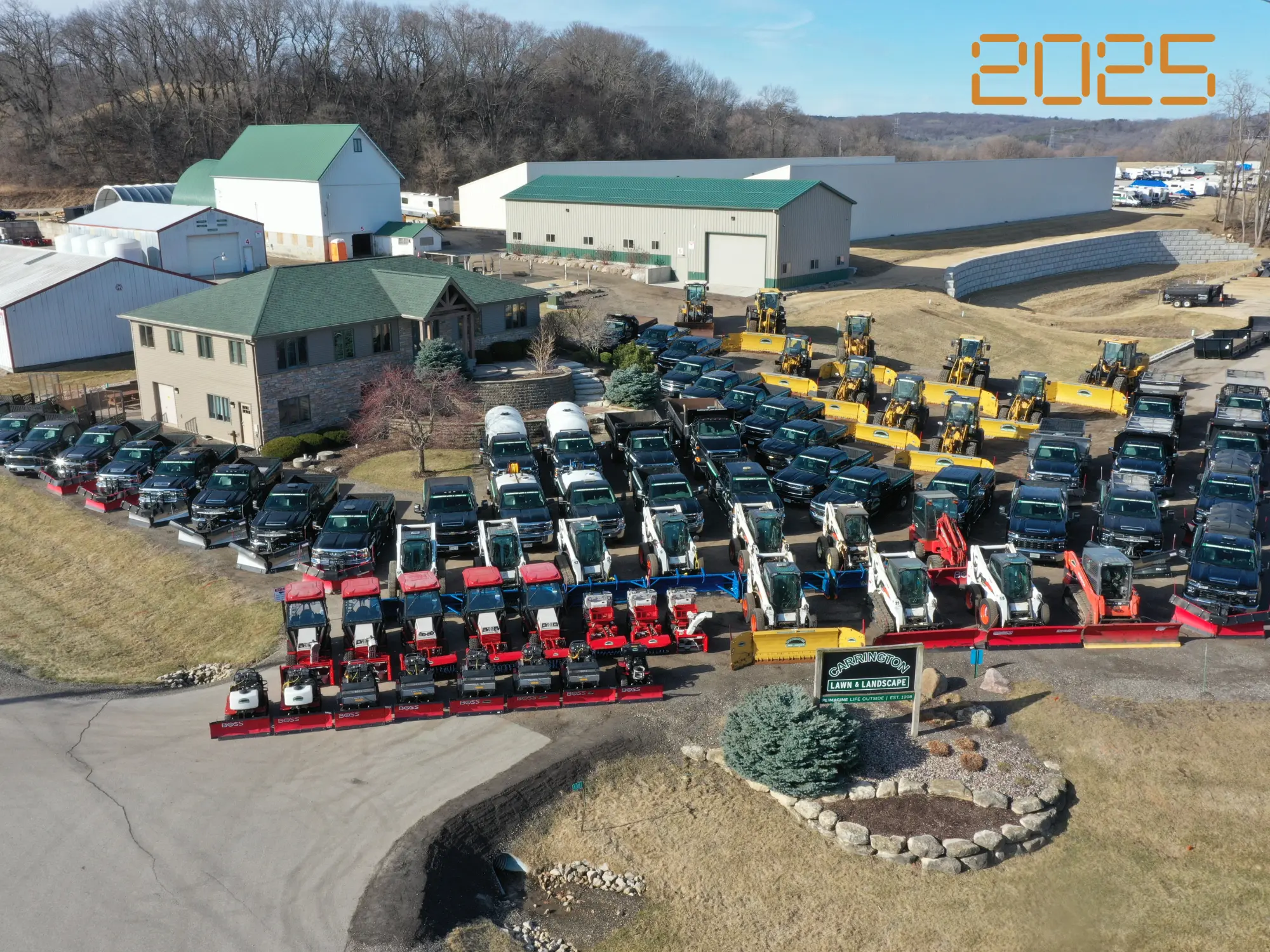 Aerial view of organized rows of plow trucks, loaders, and skid steers prepared for a commercial snow removal service by Carrington Lawn & Landscape in Middleton, Madison, and the greater Dane County area
