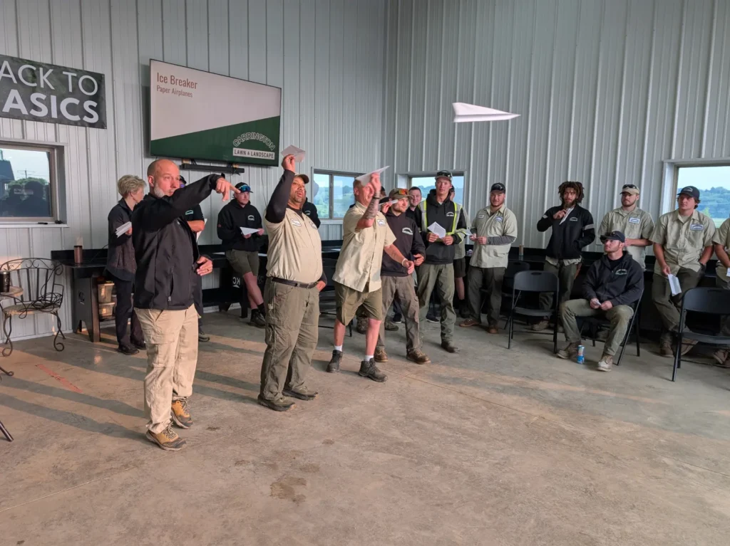 Carrington Lawn & Landscape team members throwing paper airplanes inside the Madison office during a meeting