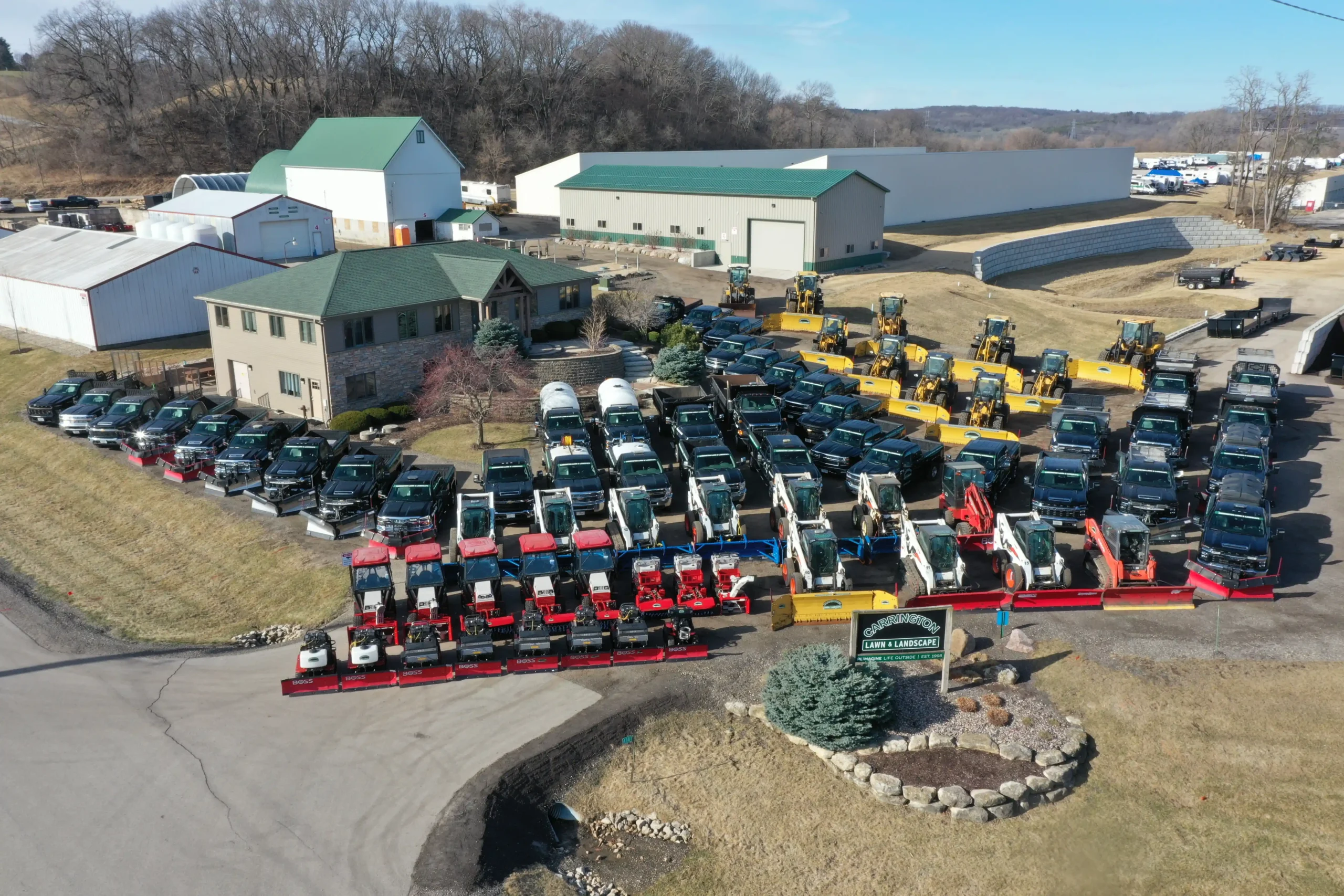 Aerial view of organized rows of plow trucks, loaders, and skid steers prepared for a commercial snow removal service by Carrington Lawn & Landscape in Middleton, Madison, and the greater Dane County area