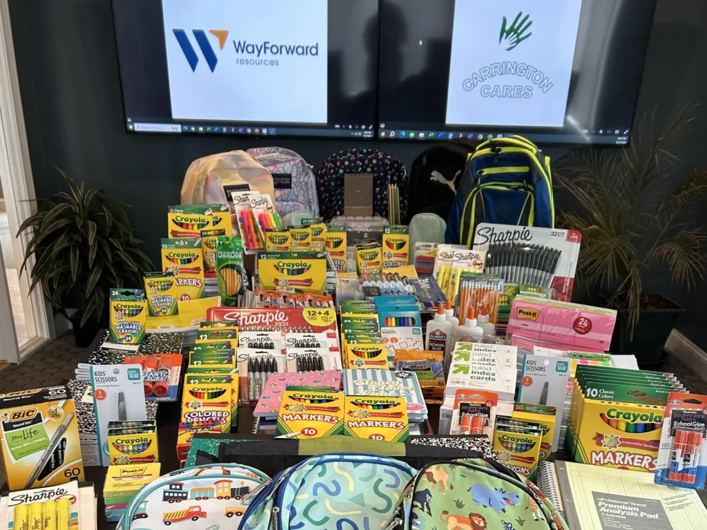 Piles of school supplies and backpacks collected by Carrington Lawn & Landscape in Madison during the Carrington Cares community drive