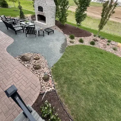 Outdoor fire pit landscape design trends featuring a modern stone fireplace, patio seating, and curved garden beds in Middleton, WI
