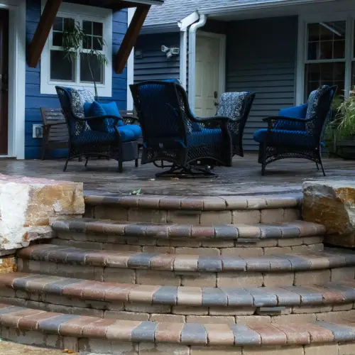 Elegant outdoor living space with custom stone patio, fire pit, and accent lighting by Carrington Lawn & Landscape in Middleton, WI