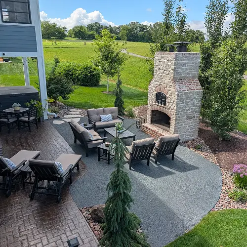 Outdoor living patio featuring stone fireplace and lounge area by Carrington Lawn & Construction in Middleton, WI