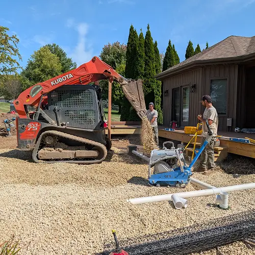 Construction crew and excavator preparing site for patio installation by Carrington Lawn & Construction in Middleton, WI