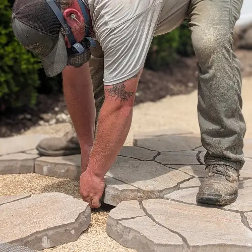Skilled patio contractor installing stone pavers for custom patio design by Carrington Lawn & Construction in Middleton, WI