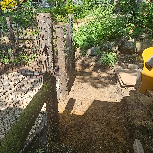 Site preparation for dry creek bed drainage system in Madison WI by Carrington Lawn & Landscape, showing soil grading near retaining wall