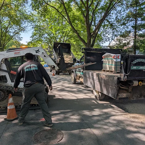 Workers loading materials and coordinating equipment for landscape project preparation by Carrington Lawn & Landscape in WI