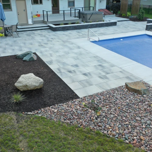 Modern poolside landscape design featuring stone patio and poolside hardscaping by Carrington Lawn & Landscape in Monona, WI