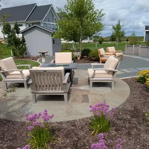 Comfortable patio furniture and blooming garden surrounding a bluestone patio landscape design by Carrington Lawn in Middleton, WI