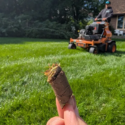 A close up of a soil core plug held in front of a lawn aerator for care for new landscaping by Carrington Lawn & Landscape in WI
