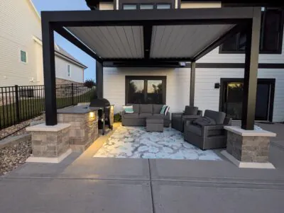 A covered patio with a built-in fire pit and seating area showing a DeForest patio and fire pit project in Middleton by Carrington Lawn & Landscape.