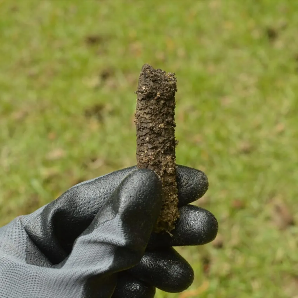 A gloved hand holding a a soil for lawn aeration in Middleton, WI