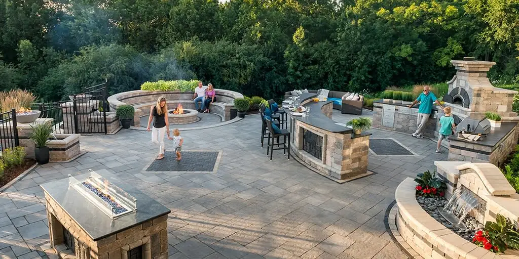 multi-level hardscape design patio witha built-in fire pit, outdoor kitchen, and seating areas
