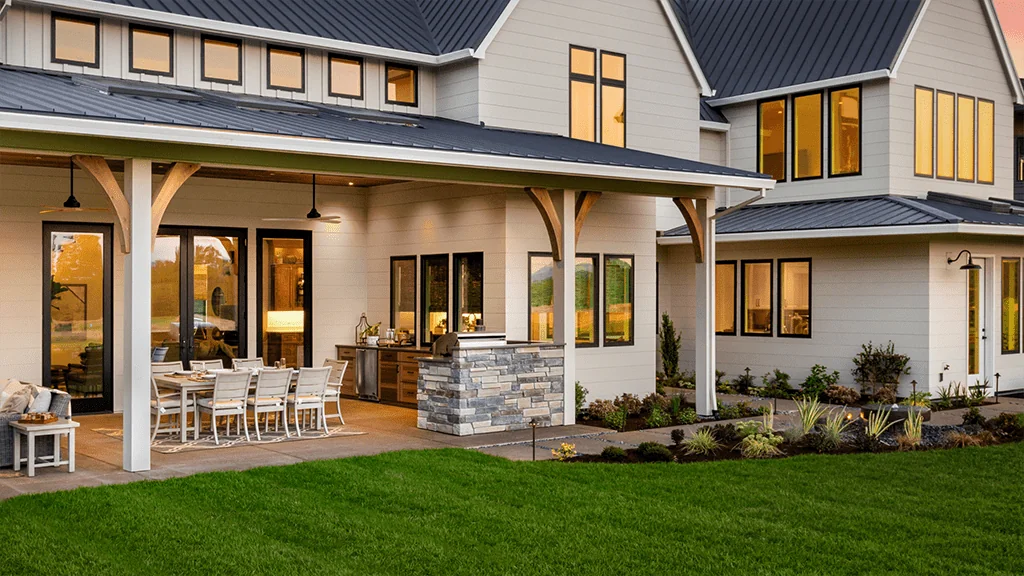 Two-story farmhouse with light gray siding, black trim, and a patio for landscape design build in Middleton, WI