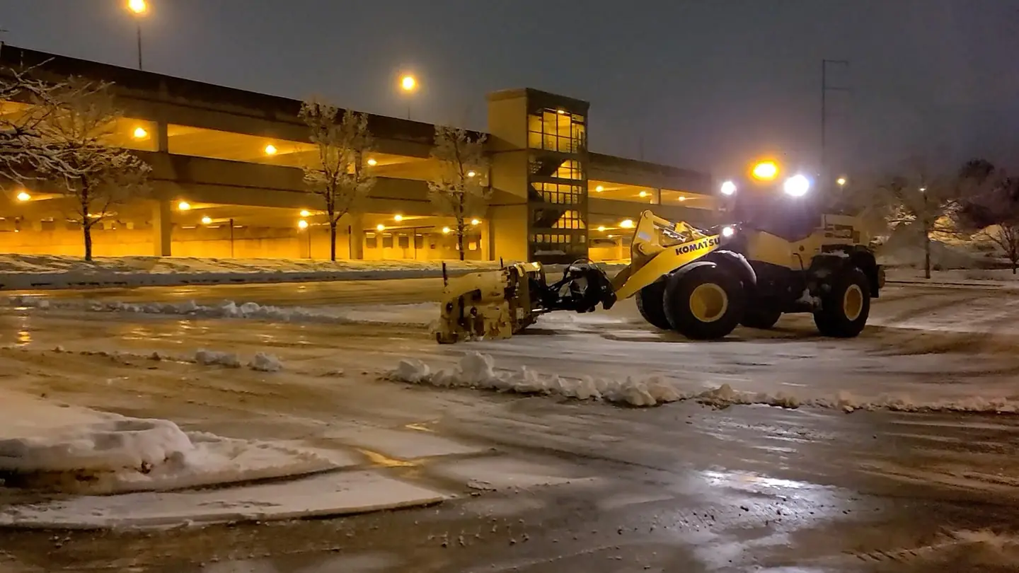 A snowmobile clearing equipment in a parking lot at night for snow and ice managememt by Carrington Lawn & Landscape in Middleton, WI.