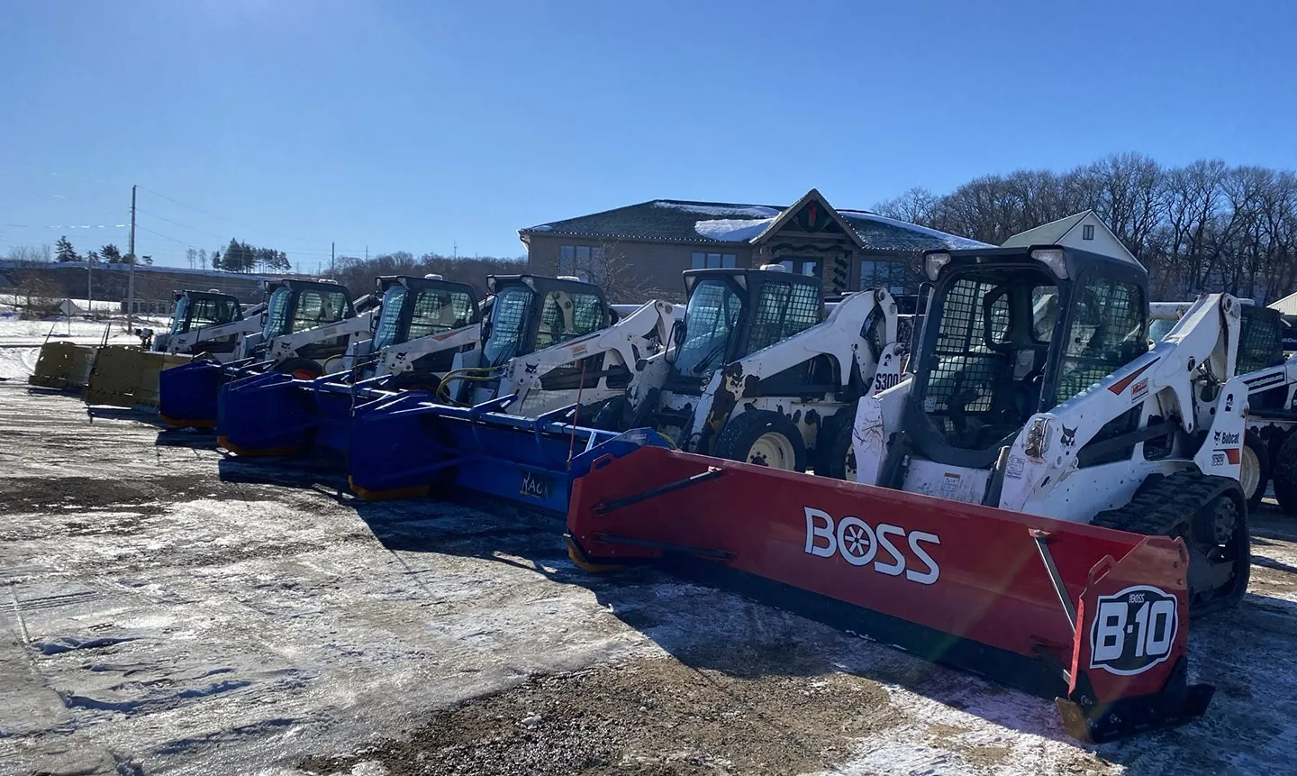 large group of pickup trucks, snow plows, and other landscaping equipment by Carrington Lawn & Landscape.