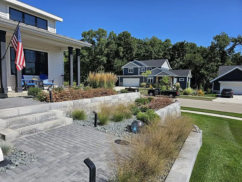 Front view of a house with a stone retaining wall and landscaping that includes ornamental grasses that had softscape landscaping in Middleton, WI