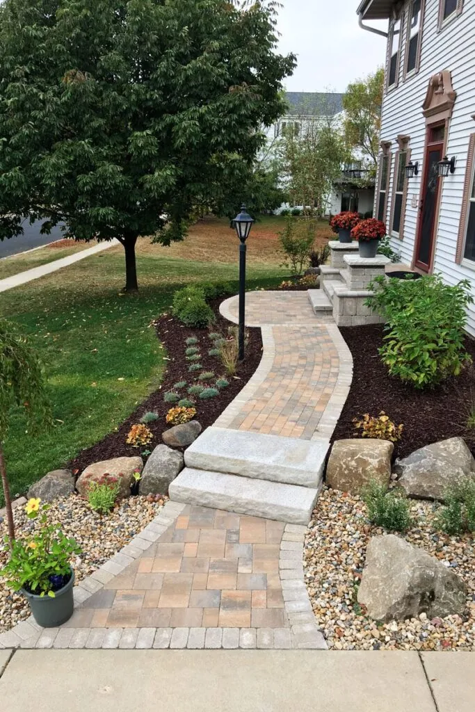 A hardscape design front yard featuring a curved walkway constructed of rectangular pavers in Middleton, WI