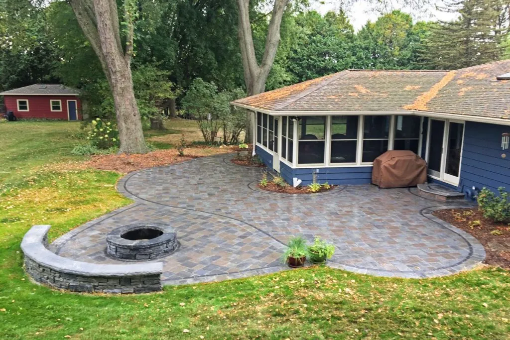 A hardscape design paved patio with a fire pit, built-in seating, and a landscaped border