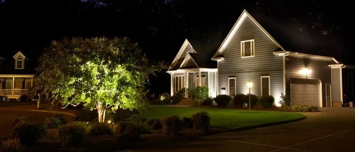 A house illuminated by landscape lighting design at night, highlighting the trees, shrubs, and driveway in Middleton, WI