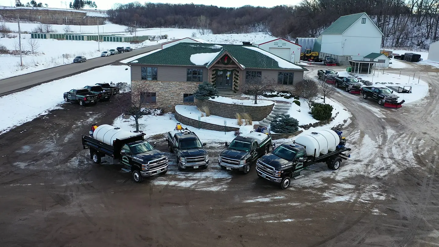 Aerial view of a large group of pickup trucks, snow plows, and other landscaping equipment by Carrington Lawn & Landscape.