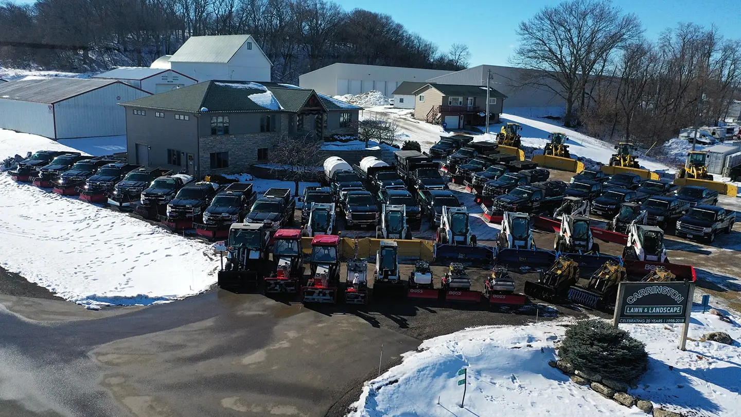 Aerial view of a large group of pickup trucks, snow plows, and other landscaping equipment by Carrington Lawn & Landscape.
