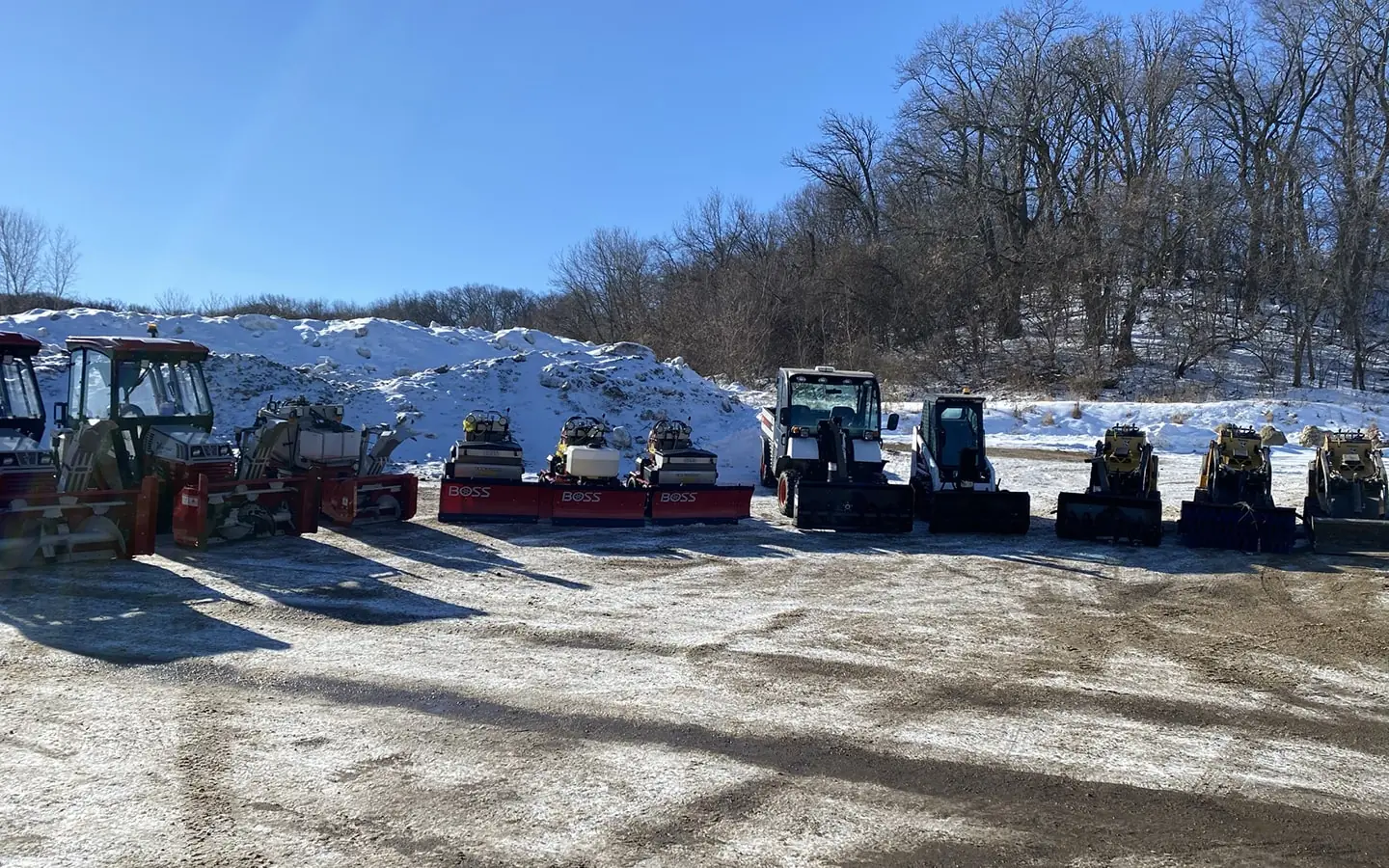 large group of pickup trucks, snow plows, and other landscaping equipment by Carrington Lawn & Landscape.