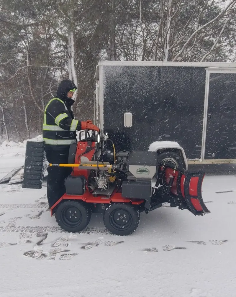 A Carrington Lawn & Landscape crew member operating a snowrator for snow and ice management in Madison, WI