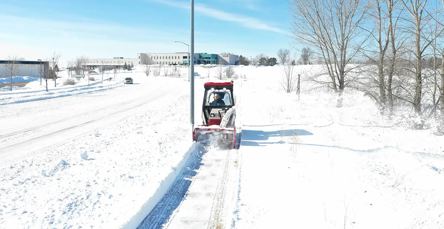 A Carrington Lawn & Landscape crew member operates a snow blower for snow and ice management in Madison, WI