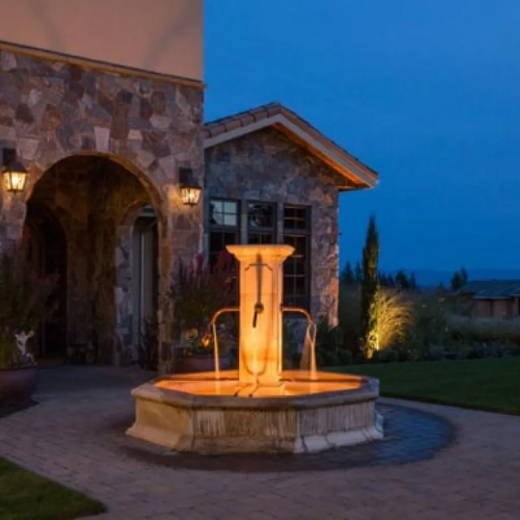 A tiered fountain illuminated with warm landscape lighting design in front in Middleton, WI