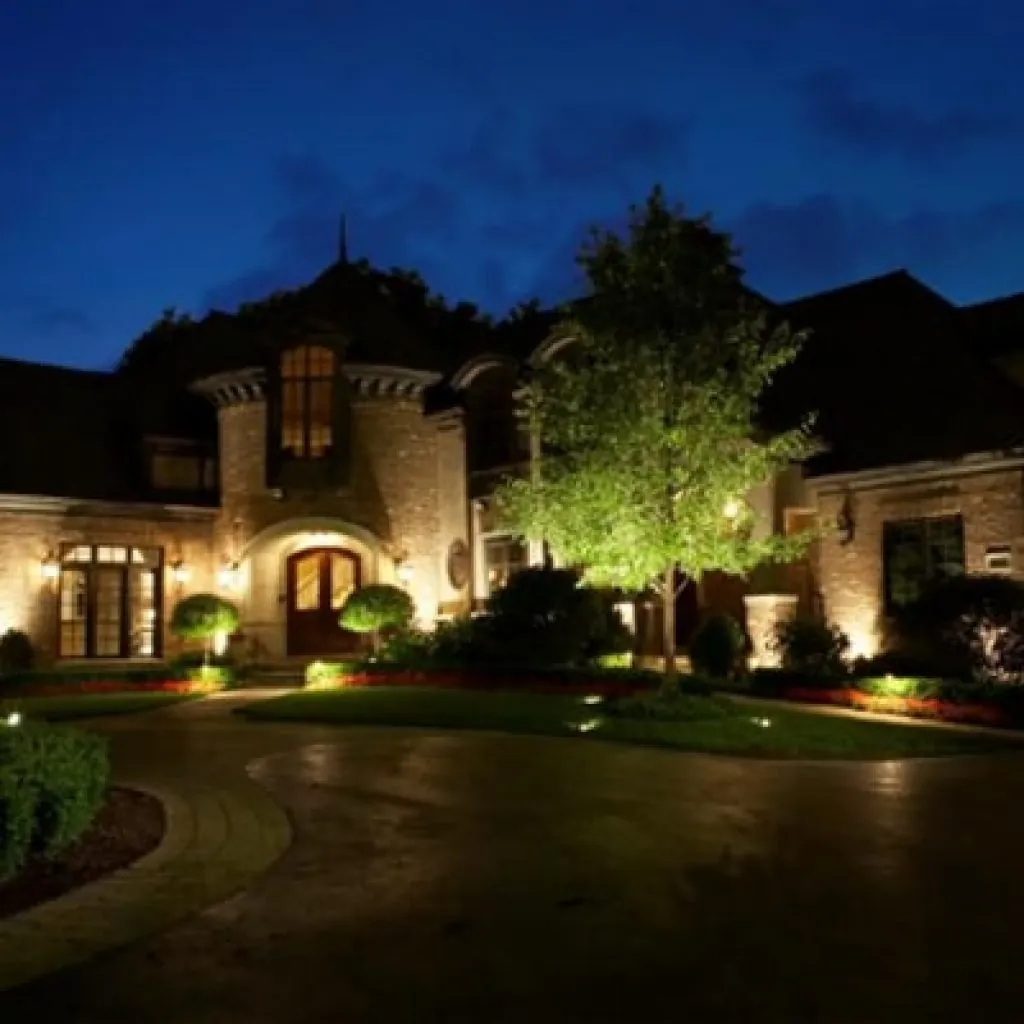 A large house with a circular driveway illuminated by various landscape lighting design fixtures at night in Middleton, WI