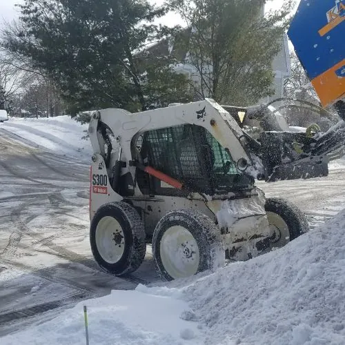 Bobcat S300 skid-steer loader clearing snow in a residential area, highlighting snow and ice removal in Madison, WI