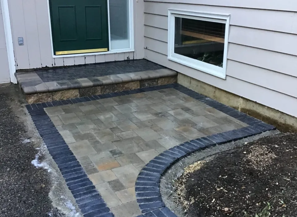 Custom hardscape design in Madison, WI, featuring a stylish paver patio with a contrasting border and a matching stone step for a polished entryway