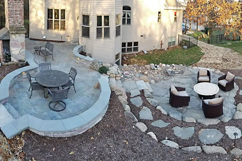 Elegant outdoor living space featuring a multi-level stone patio, fire pit, and seating areas expertly crafted through a landscape design build by Carrington Lawn & Landscape.