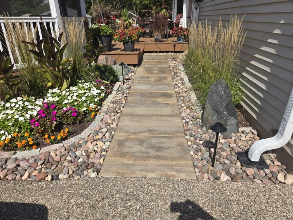 Pathway with stone border and landscaping, showcasing hardscape design leading to a house entrance.