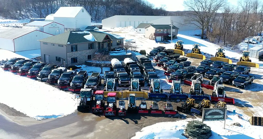 Aerial view of a large group of pickup trucks, snow plows, and other landscaping equipment by Carrington Lawn & Landscape.
